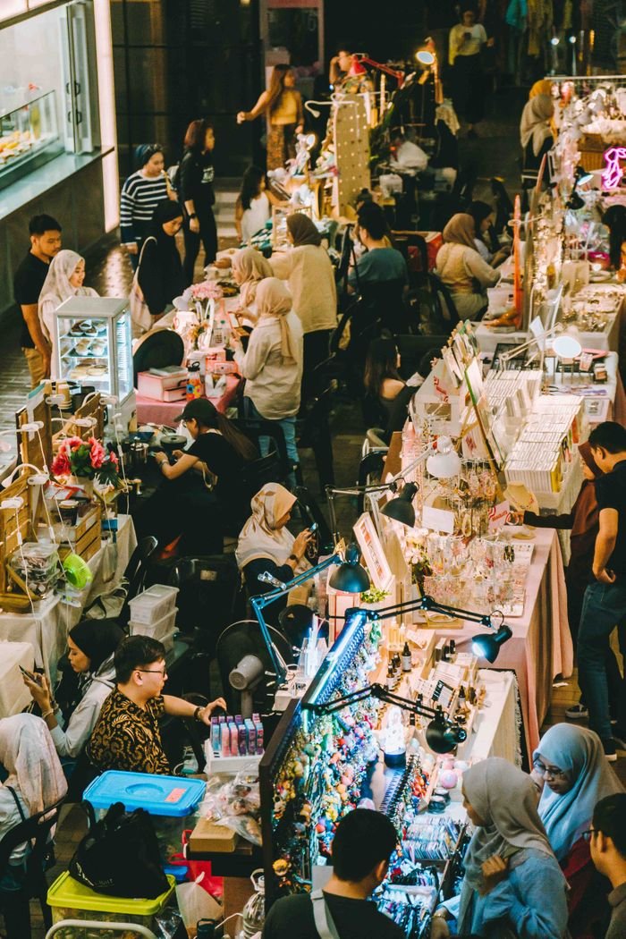 A lively scene at a night market in Kuala Lumpur showcasing diverse stalls and people shopping.