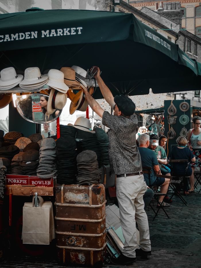 Street vendor selling hats at vibrant Camden Market, London.